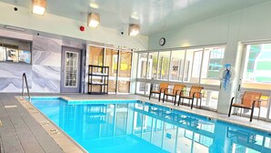 Una piscina interior con carriles delimitados, un reloj en la pared y una fila de sillas junto a las ventanas.