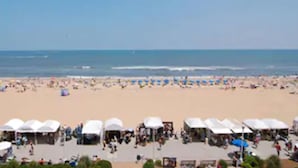 Una playa con tiendas de campaña blancas y gente.