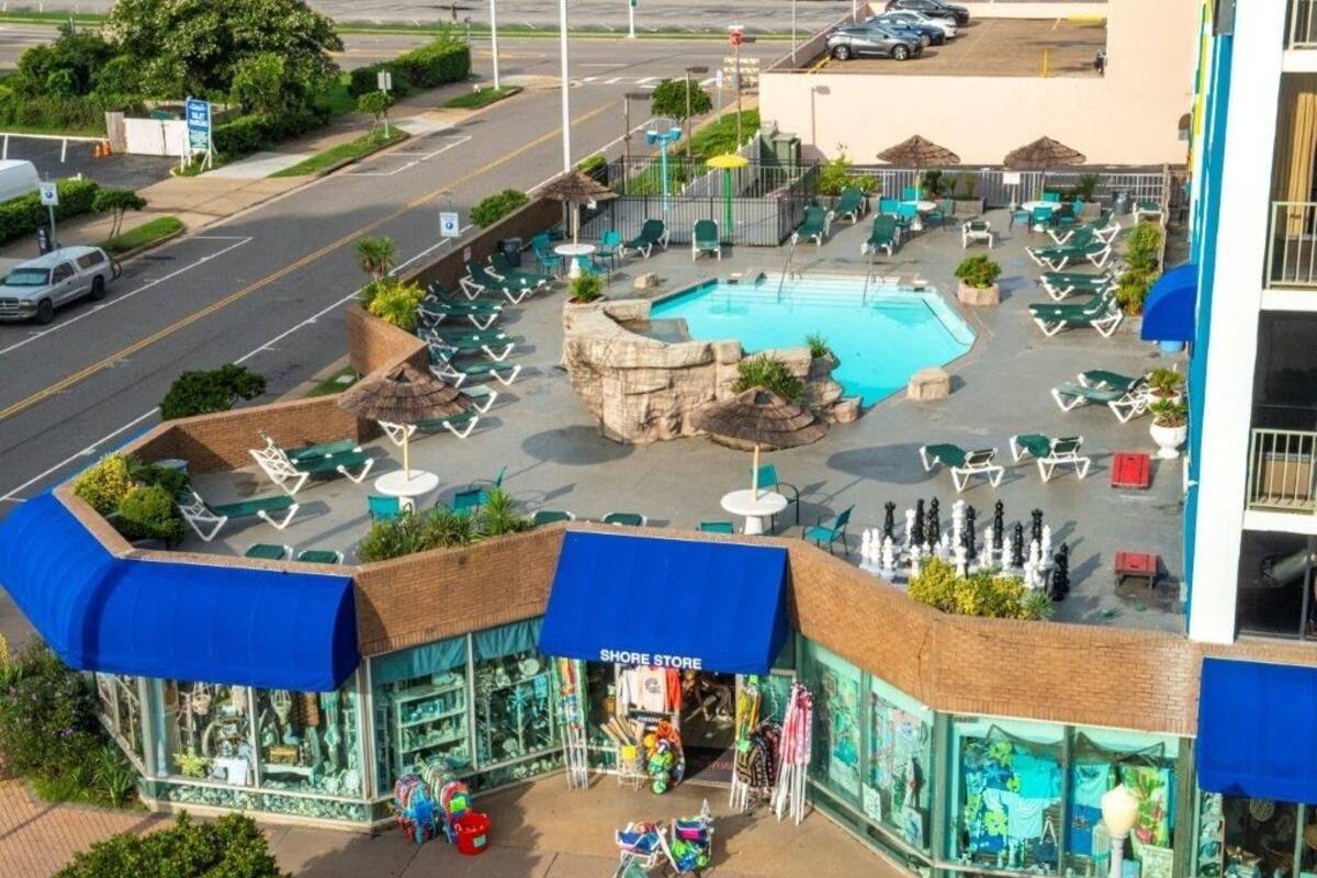 A hotel with a pool, outdoor seating, and a shop.