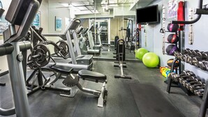 A gym with exercise equipment, a mirror, and a wall-mounted TV. - Days Inn by Wyndham Virginia Beach At The Beach (Virginia Beach)