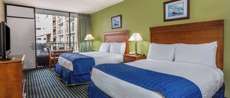 A hotel room with two beds, a desk with a chair, a TV, and a window with a view of buildings.