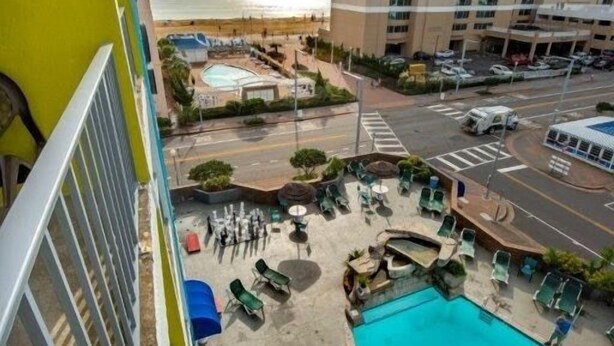 A hotel with a rooftop pool, lounge chairs, and a view of the ocean. - Days Inn by Wyndham Virginia Beach At The Beach (Virginia Beach)