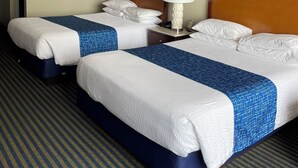 A hotel room with two beds, a nightstand, a lamp, and artwork on the wall. - Days Inn by Wyndham Virginia Beach At The Beach (Virginia Beach)