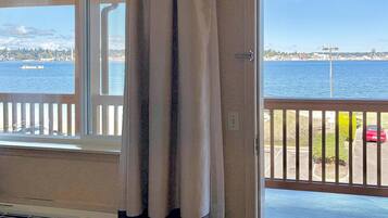 Une chambre avec vue sur un plan d’eau, un balcon avec une balustrade et une porte avec un rideau.