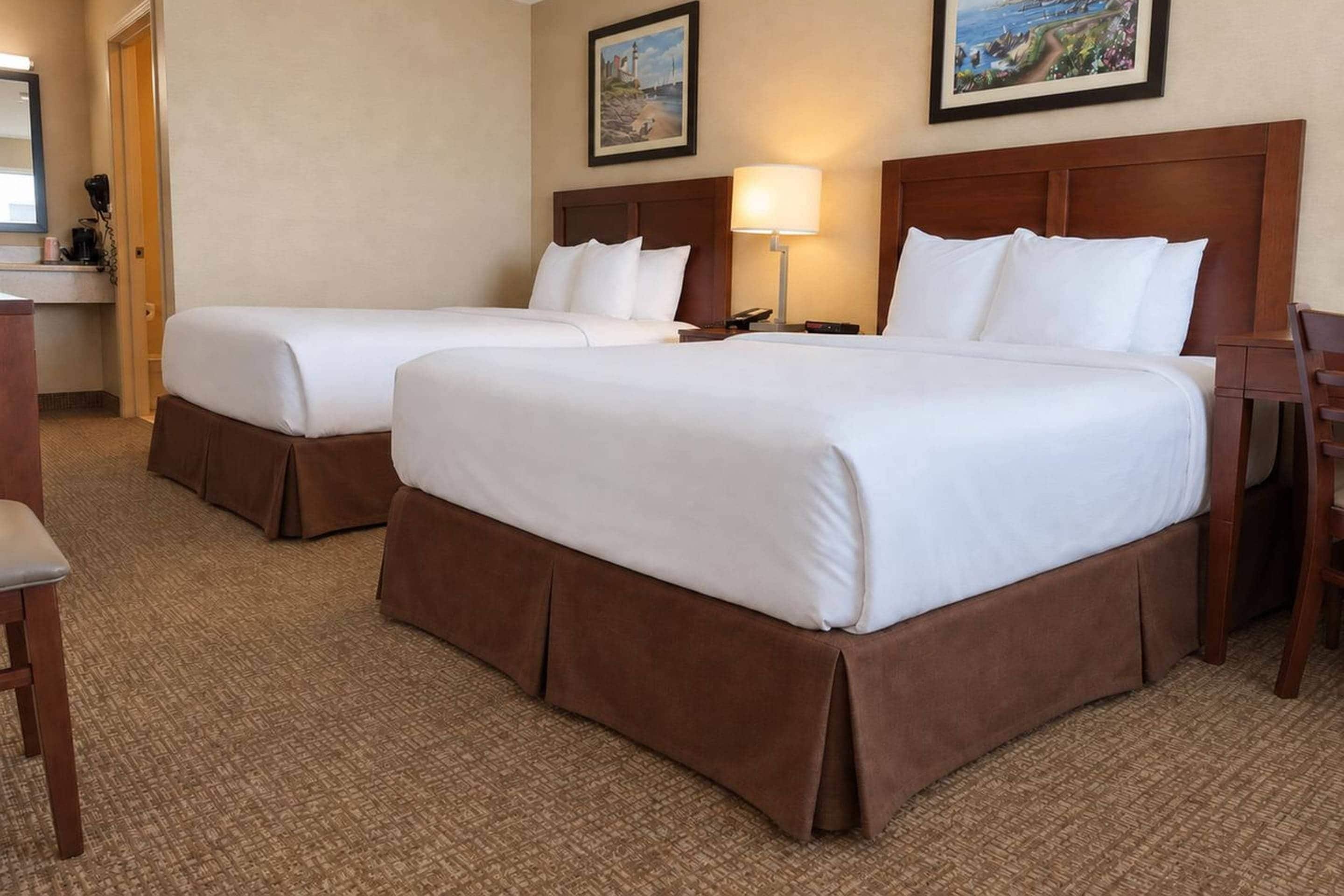 A hotel room with two beds, a desk, and a chair.