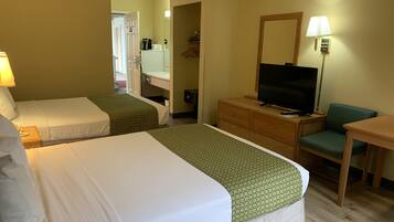 A hotel room with two beds, a television, a desk, and a chair.
