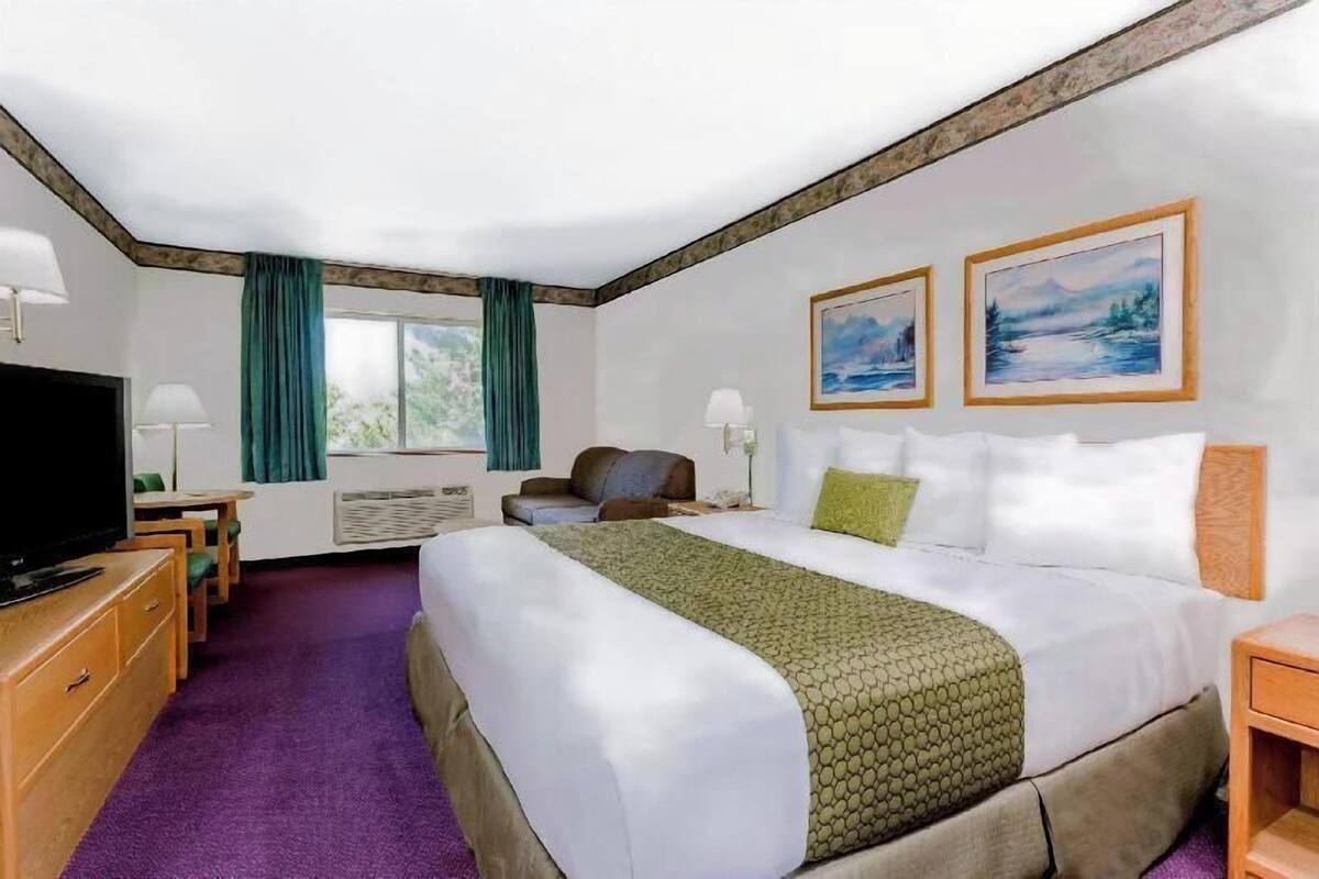 Habitación de hotel con una cama grande, televisión, escritorio y dos cuadros en la pared.