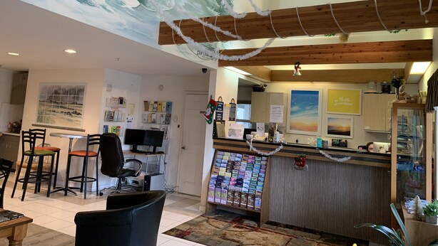A cozy indoor space with a wooden ceiling, a reception desk, and a seating area with chairs. - Days Inn by Wyndham Ocean Shores (Ocean Shores)