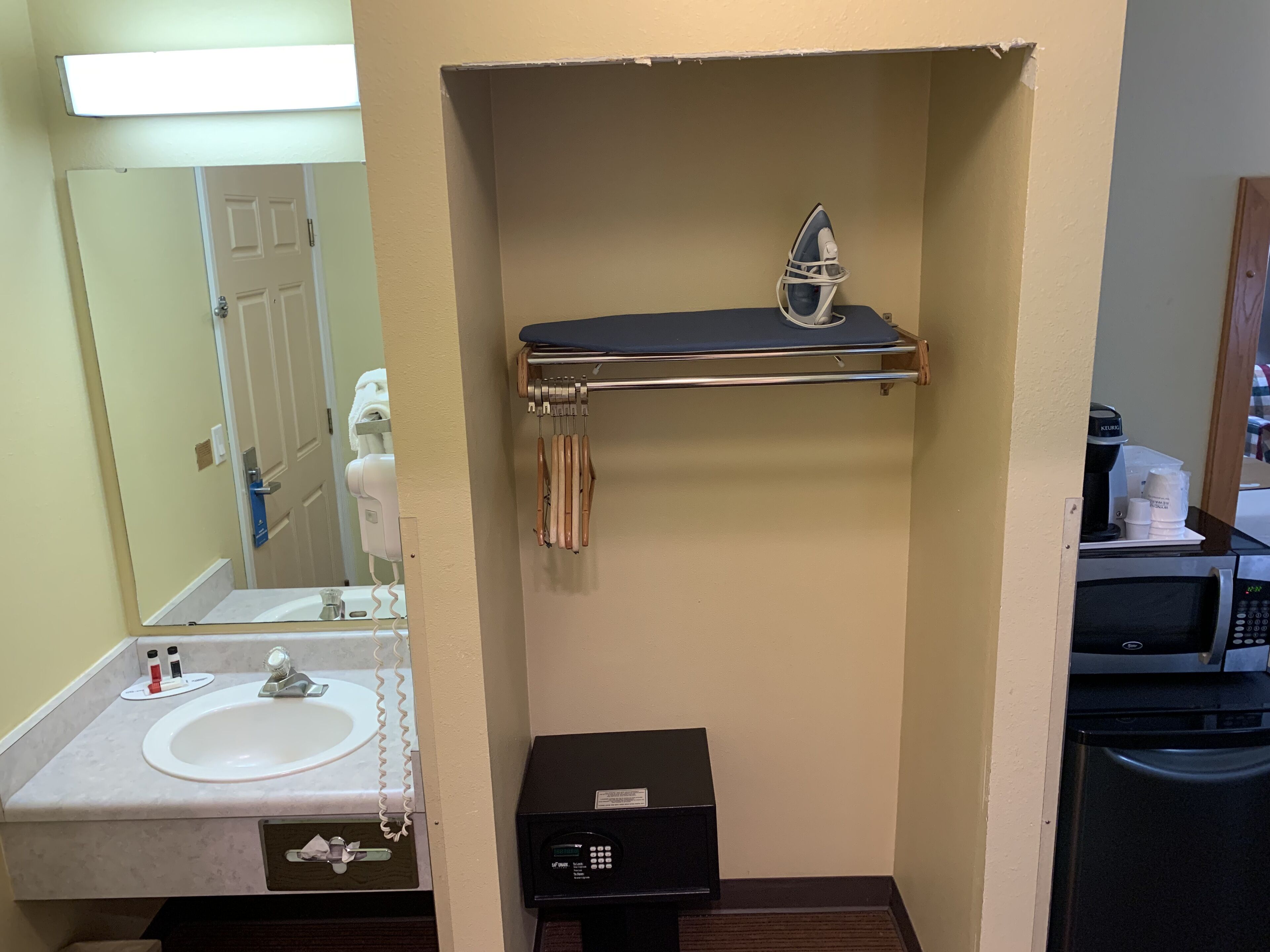 A compact bathroom with a sink, mirror, towel rack, and a small black appliance, likely a coffee maker.