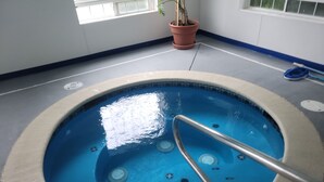 An indoor swimming pool with a metal ladder, a potted plant, and a blue tiled floor. - Days Inn by Wyndham Ocean Shores (Ocean Shores)