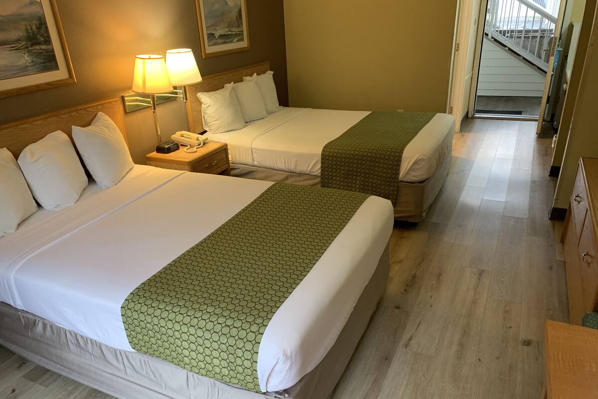Habitación de hotel con dos camas, una mesita de noche con teléfono y una escalera que sube a un piso superior.