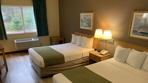 A hotel room with two beds, a window with curtains, a bedside table with a lamp, and a wall-mounted phone. - Days Inn by Wyndham Ocean Shores (Ocean Shores)
