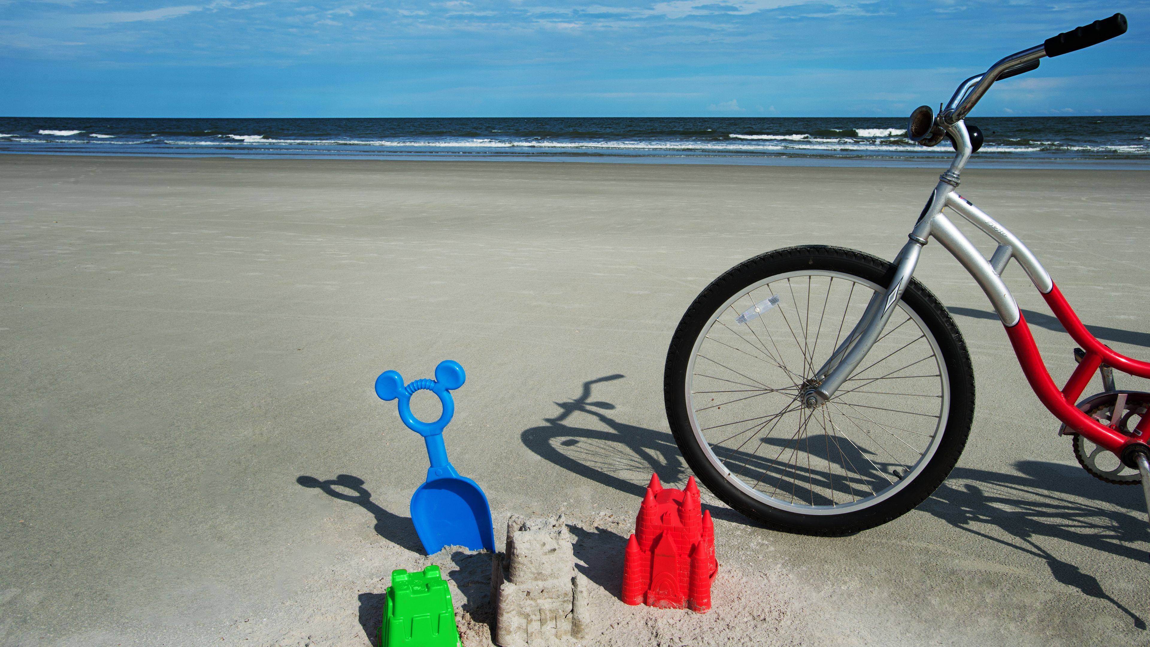 A bicycle on a sandy beach with a clear view of the ocean in the background.