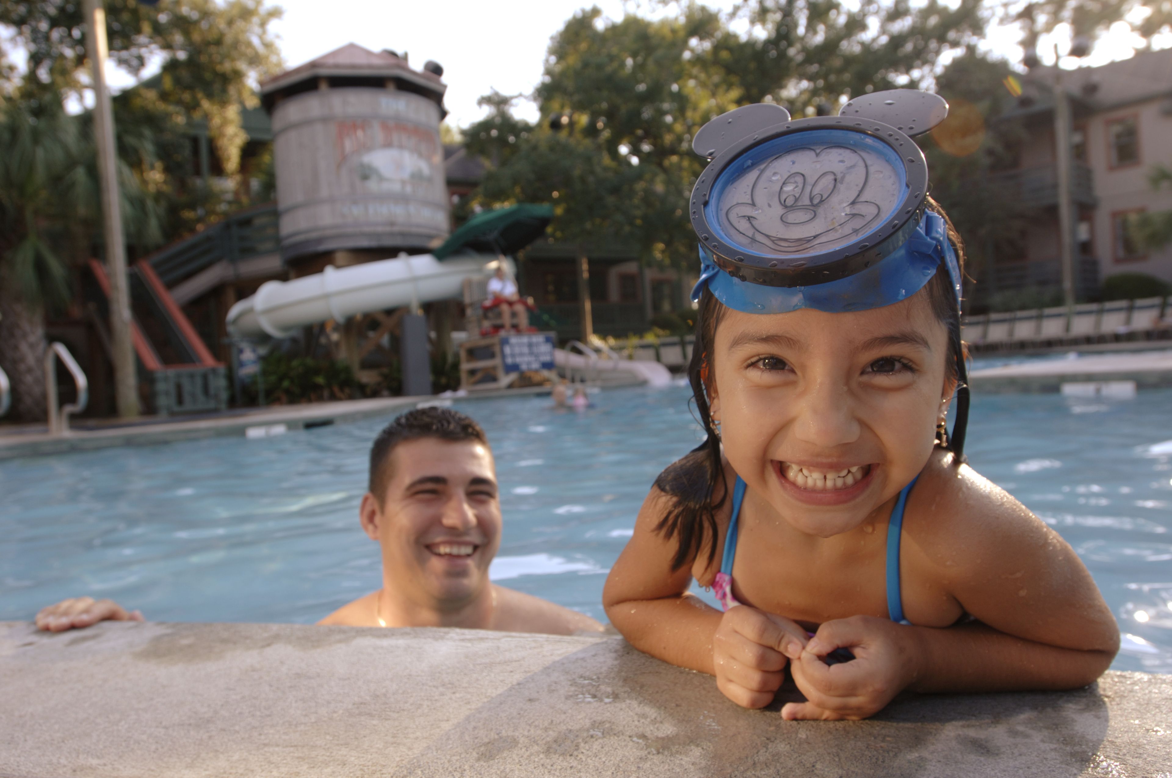 Ein Schwimmbecken mit Wasserrutsche und einem Wasserturm im Hintergrund.