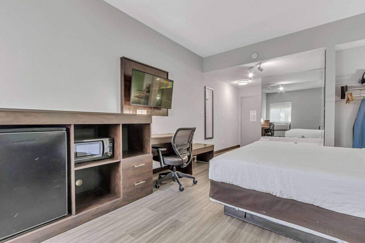 Une chambre d’hôtel équipée d’un lit, d’un bureau avec une chaise, d’une télévision et d’un four à micro-ondes.