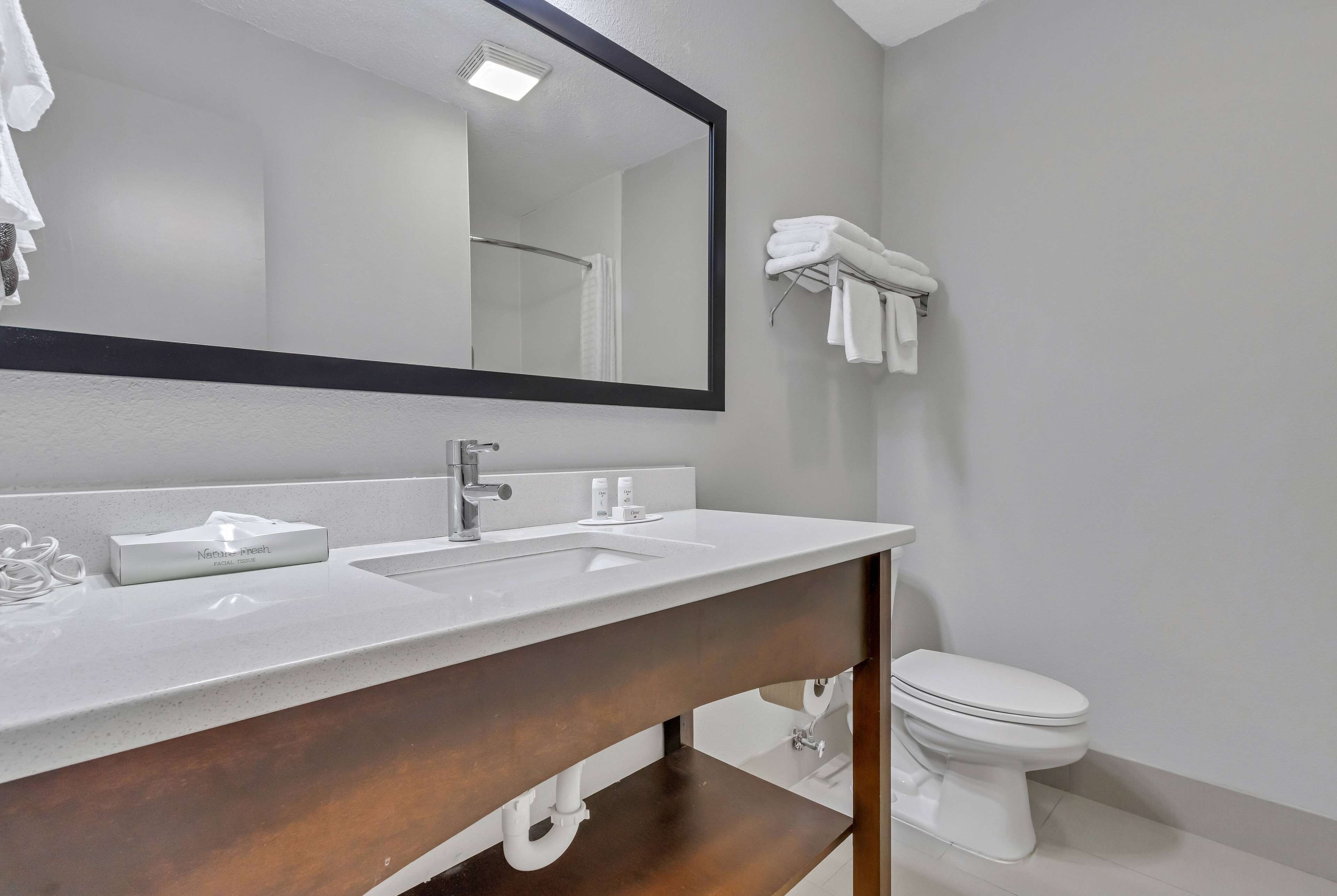 A bathroom with a white sink, a mirror, a toilet, and a towel rack.
