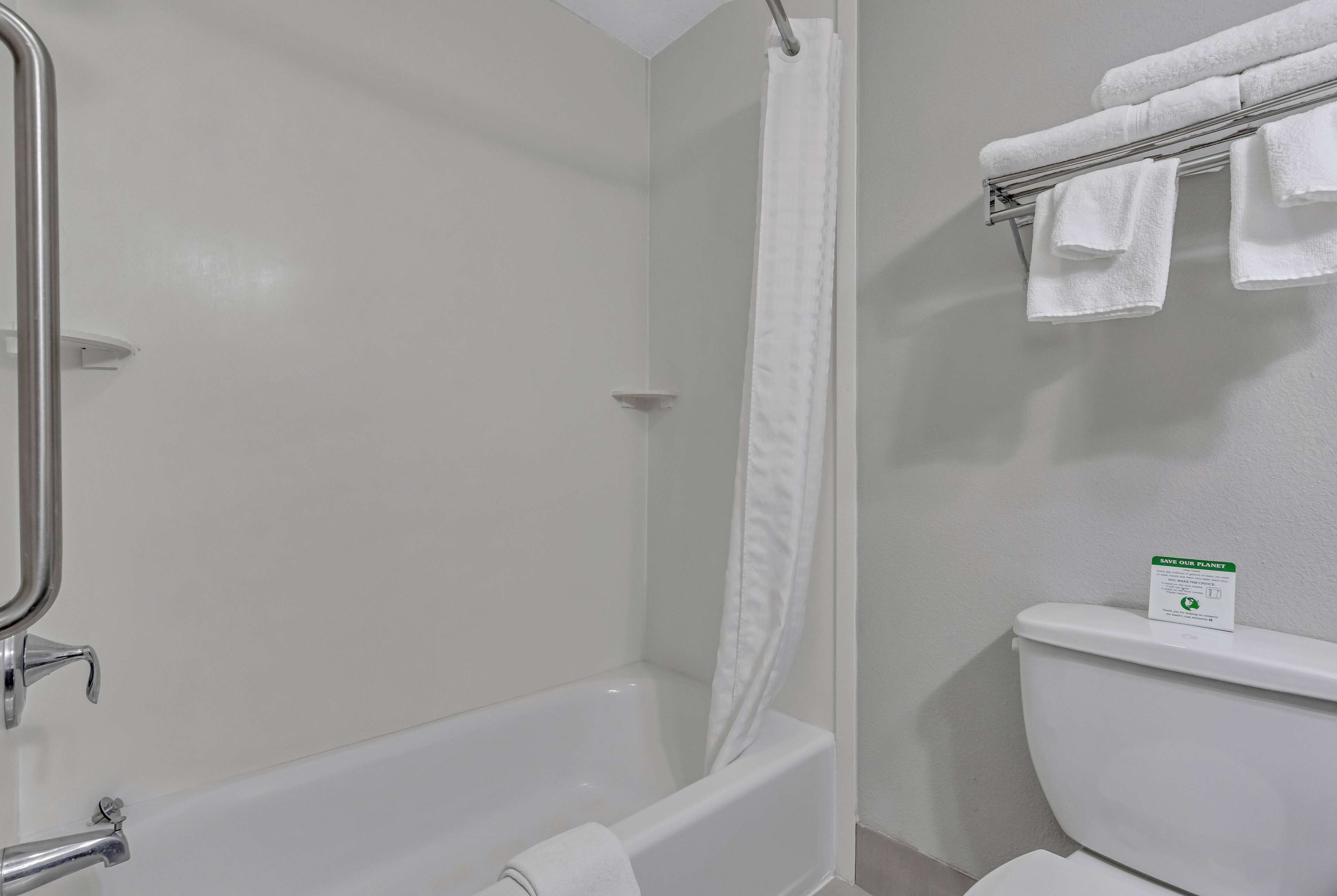 A bathroom with a bathtub, a shower curtain, a toilet, and a towel rack with towels.