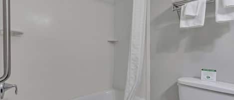 Um banheiro com banheira, cortina de chuveiro, vaso sanitário e porta-toalhas com toalhas.