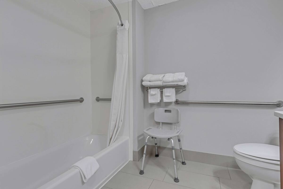 Une salle de bain équipée d’une douche, de toilettes et d’un banc accessible aux personnes en fauteuil roulant.