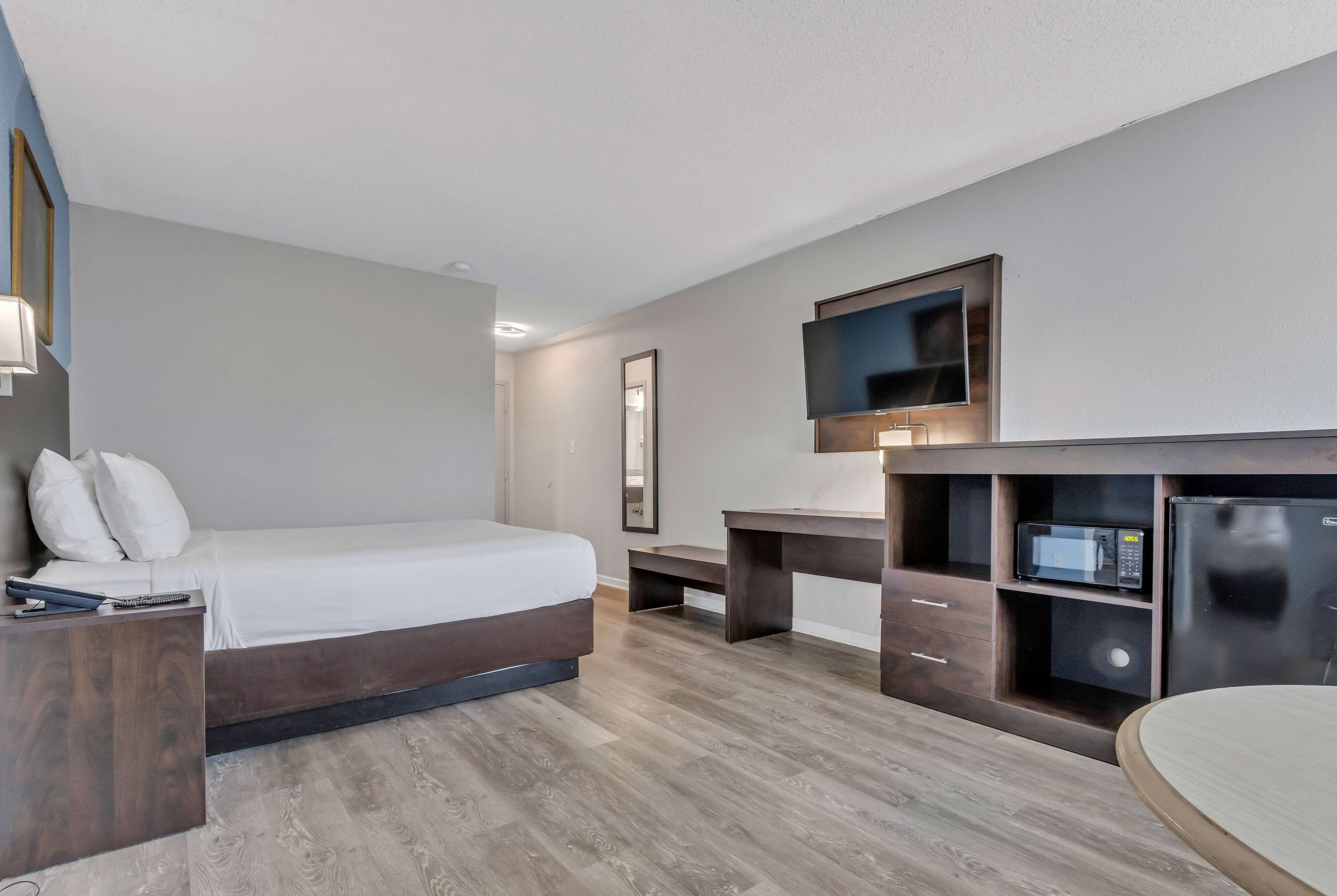 Una habitación de hotel moderna con cama, escritorio y televisión integrada.