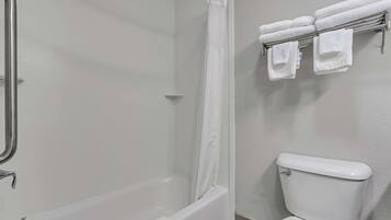 Un baño con bañera, cortina de ducha, inodoro y toallero con toallas.