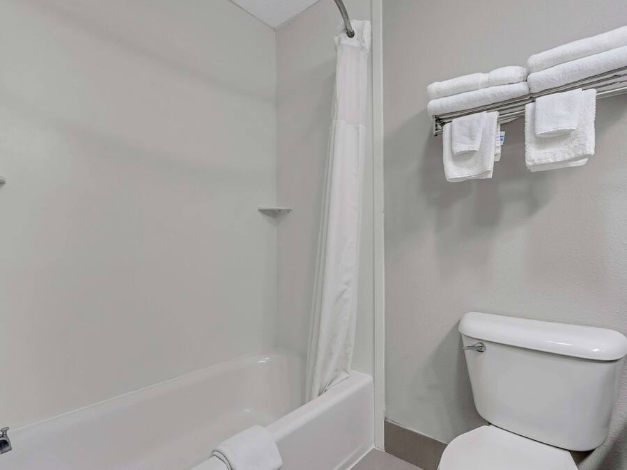 Un baño con bañera, cortina de ducha, inodoro y toallero con toallas.