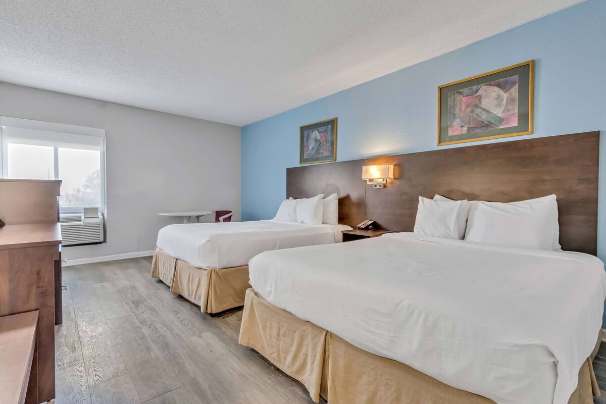 Une chambre d’hôtel avec deux lits, un bureau et une fenêtre.
