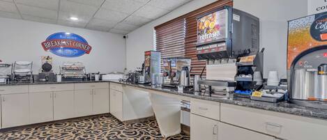 A breakfast area with a sign reading "Baymont Breakfast Corner," a coffee machine, and a beverage dispenser.