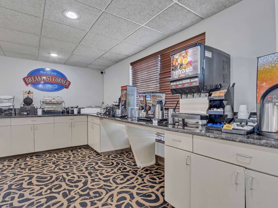 Un área de desayuno con un cartel que dice "Baymont Breakfast Corner", una máquina de café y un dispensador de bebidas.