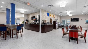 A spacious hotel lobby with a reception area, a coffee bar, and a dining area with tables and chairs. - Comfort Inn & Suites Hazelwood - St. Louis (Hazelwood)