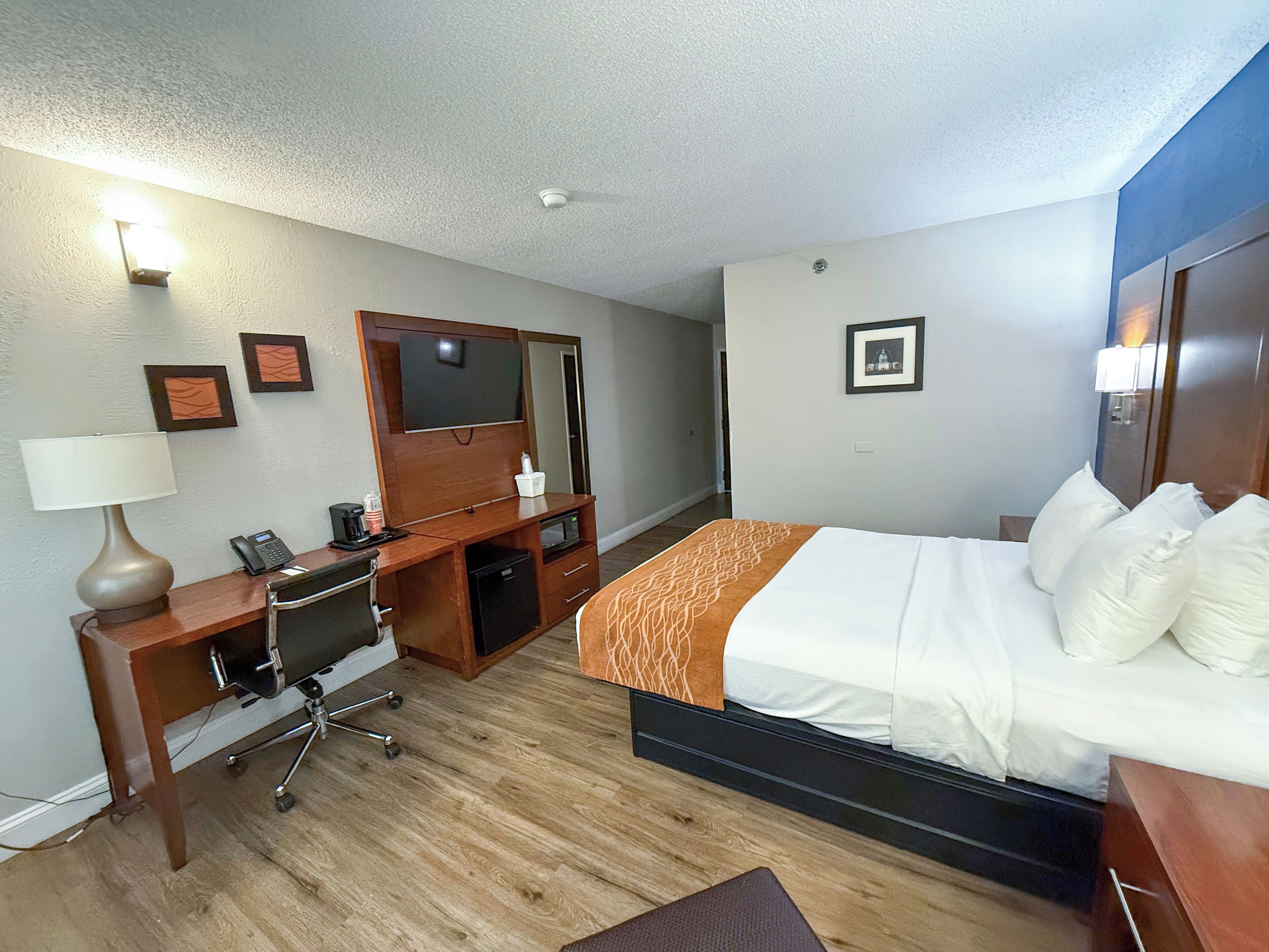 A hotel room with a bed, desk, chair, and a television.