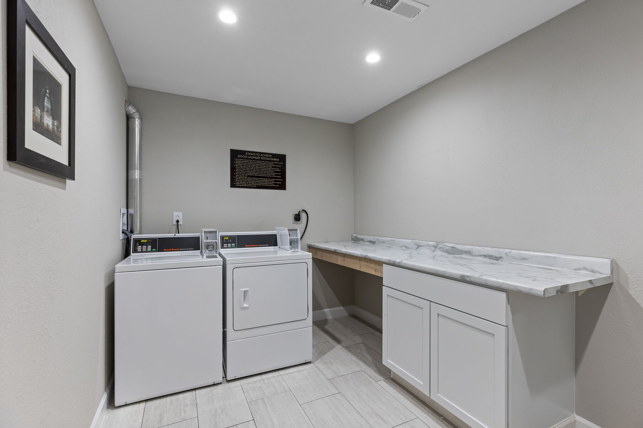 A laundry room with a washing machine, dryer, and a marble countertop.
