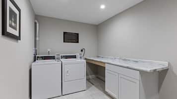 A laundry room with a washing machine, dryer, and a marble countertop.