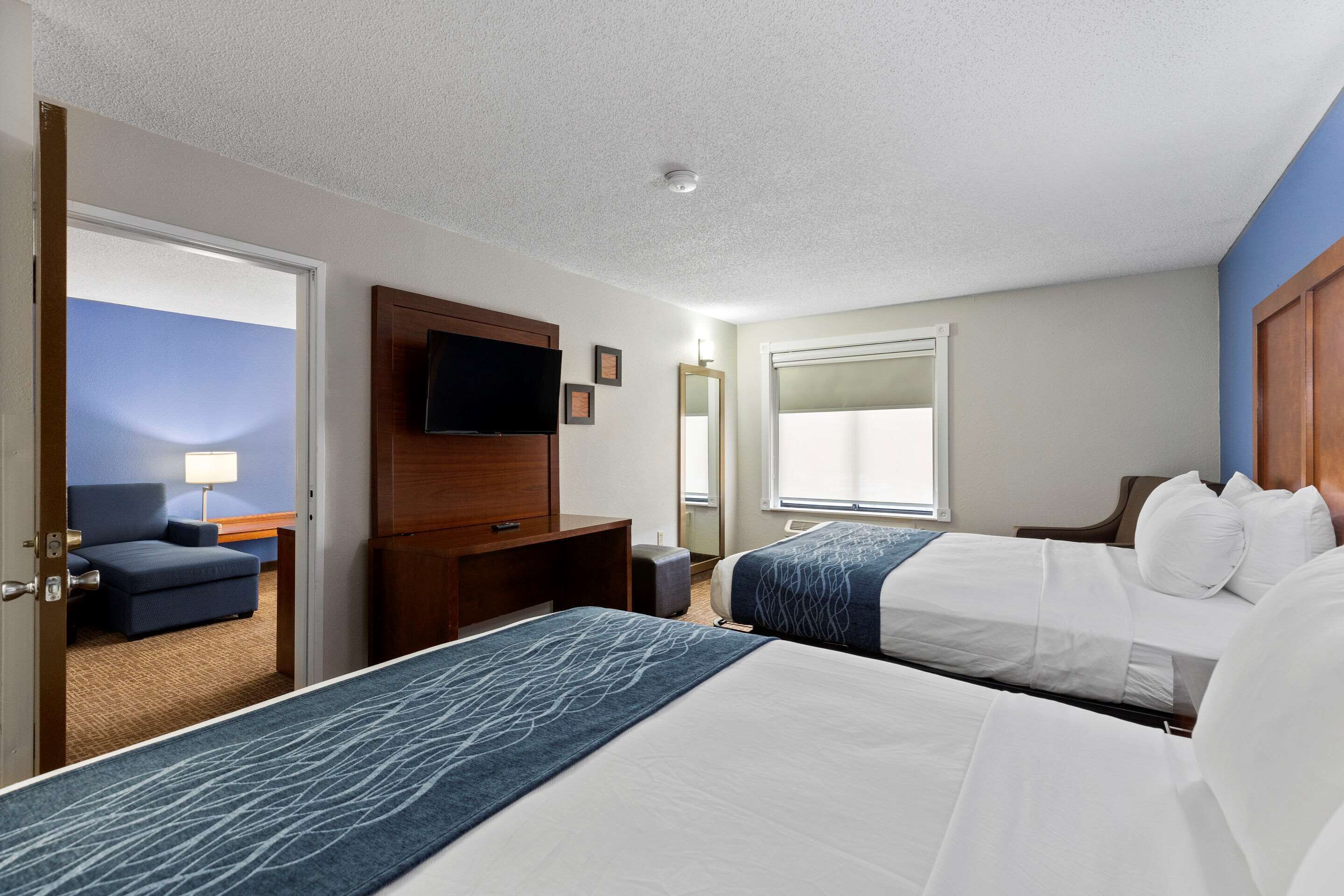Une chambre d’hôtel avec deux lits, une télévision, un bureau et une chaise.