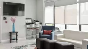 A modern living room with a white sofa, a blue armchair, and a small side table with a vase. - Comfort Inn & Suites Hazelwood - St. Louis (Hazelwood)