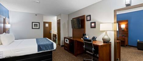 A hotel room with a bed, desk, chair, and a large mirror.