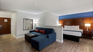 A hotel room with a large bed, a sofa, a small table, and a nightstand. - Comfort Inn & Suites Hazelwood - St. Louis (Hazelwood)