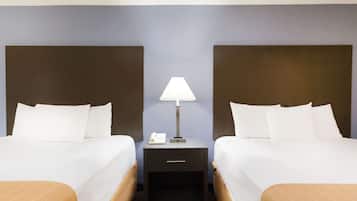 A hotel room with two beds, a nightstand with a lamp, and a drawer.