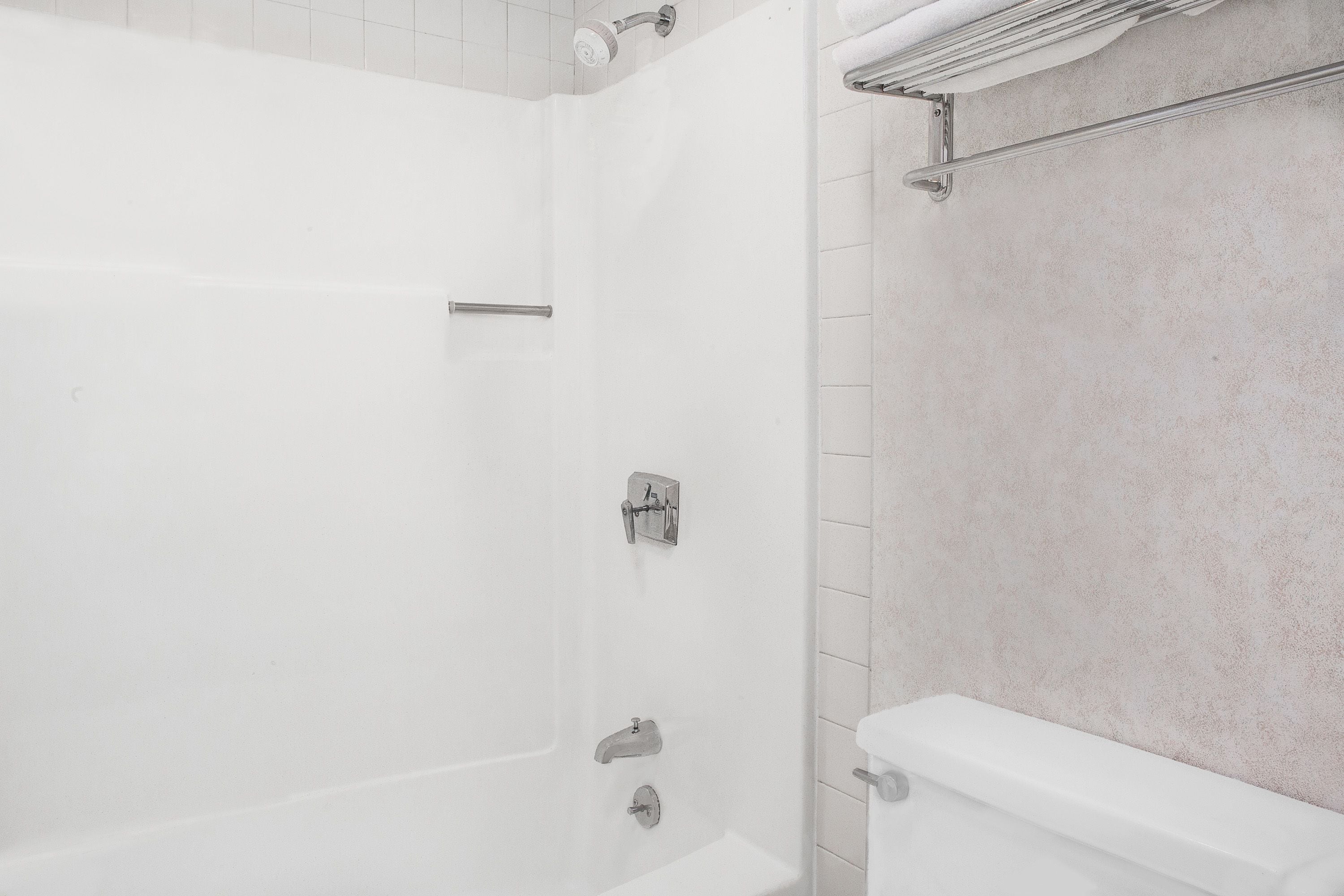 A bathroom with a shower, toilet, and towel rack.