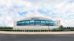 Ein modernes Gebäude mit einer gewölbten Glasfassade, mit dem Schriftzug "MOHEGAN SUN APENIA AT CARY PLAZA".