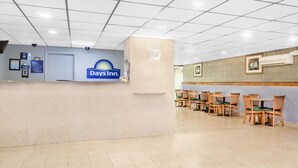 Ein Empfangsbereich eines Days Inn Hotels mit einer Theke, Stühlen und einem gefliesten Boden.