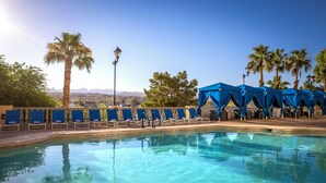 A swimming pool with clear blue water, surrounded by blue lounge chairs and a blue canopy structure.