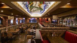 A restaurant with wooden tables, red cushioned booths, and a bar area.