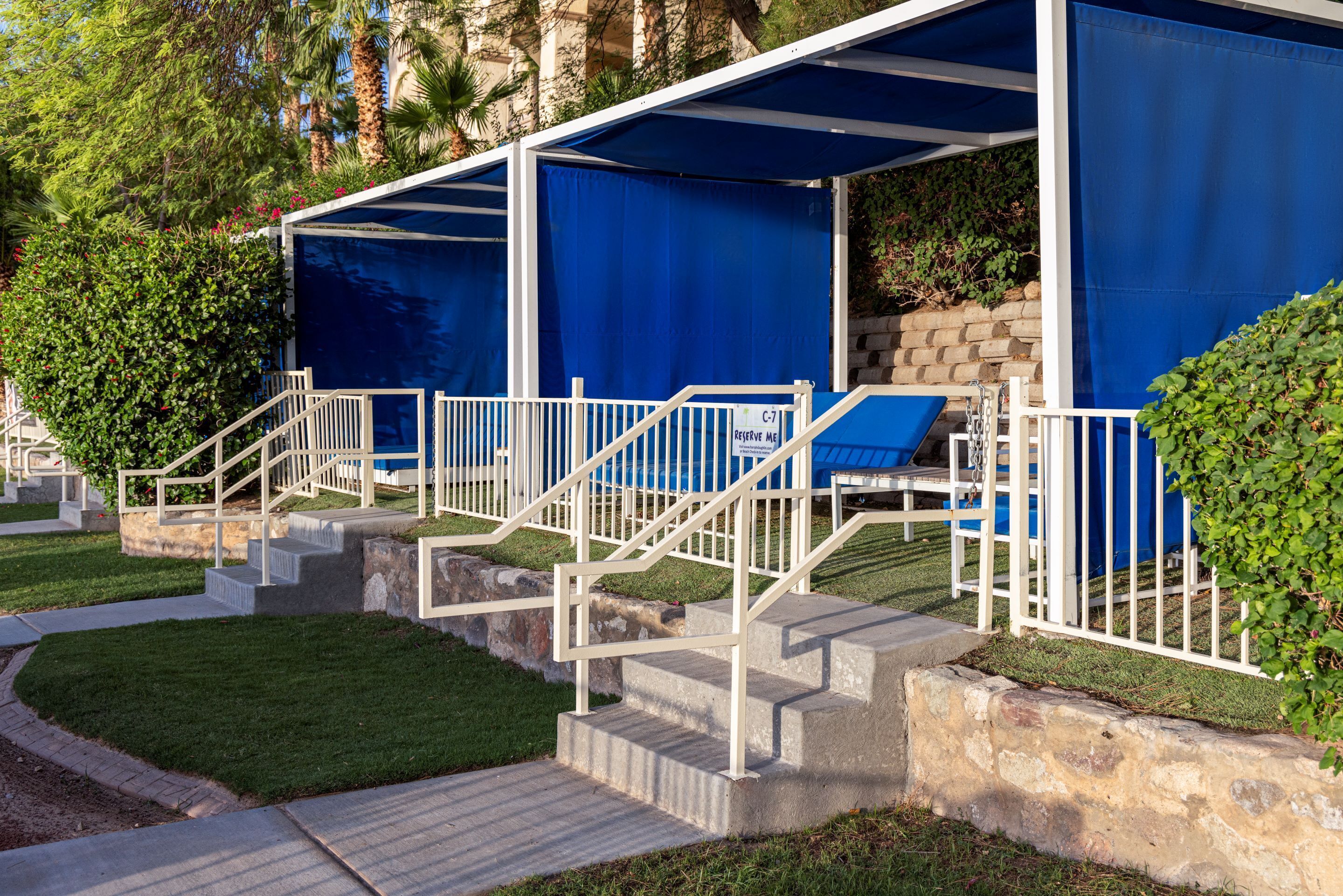 A poolside area with covered seating and a staircase leading to a pool.