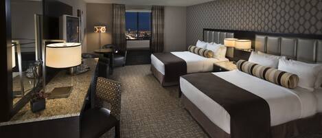 A hotel room with two beds, a desk with a lamp, a chair, a mirror, and a view of the city at night.