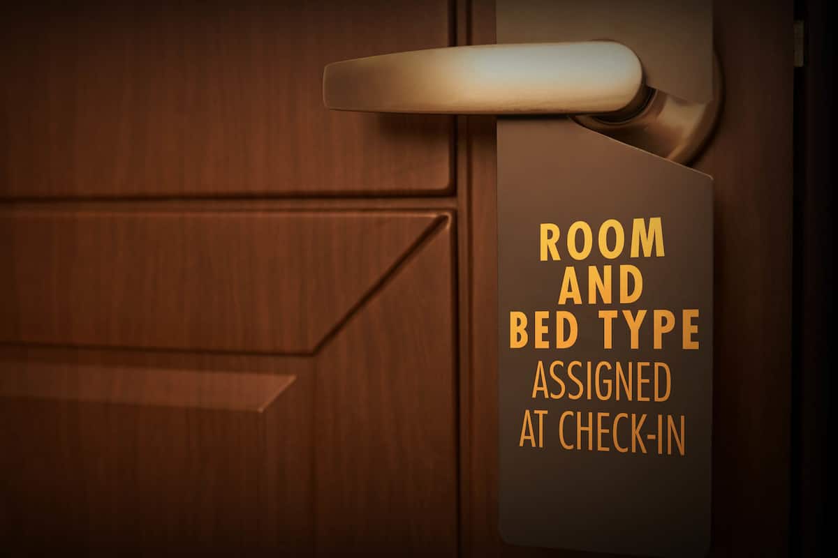 Porta com placa indicando tipo de quarto e cama atribuídos no momento do check-in.
