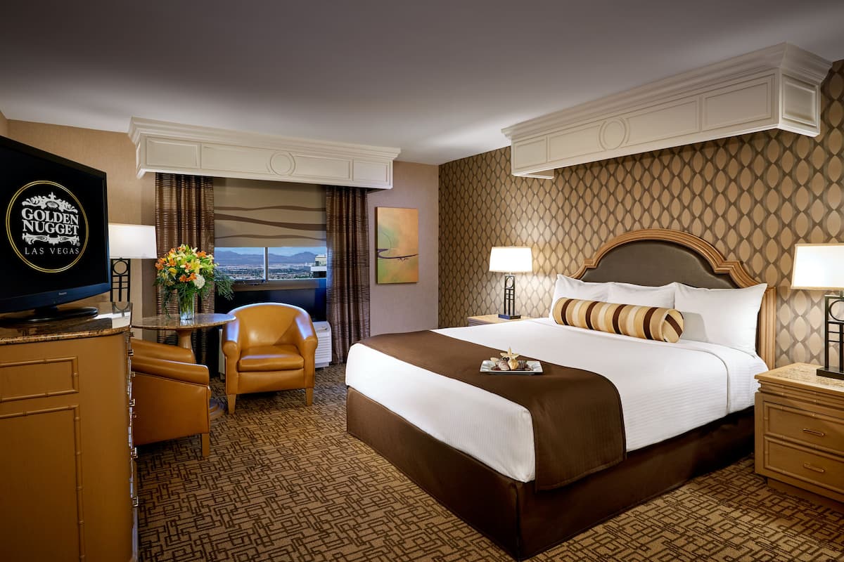 Quarto de hotel com cama, escrivaninha, cadeira, televisão e vista para a cidade.