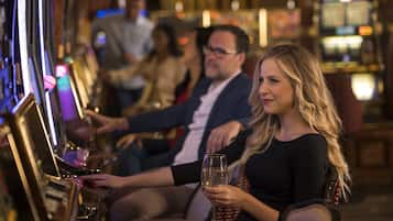 A bar area with a woman holding a glass, a man in a suit, and another person in the background.
