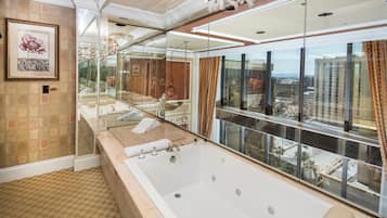 A luxurious bathroom with a large bathtub, a glass-enclosed shower area, and a view of the cityscape through large windows.