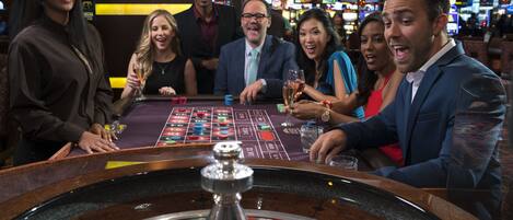 Un salón de juegos de casino con una mesa de ruleta y máquinas tragamonedas.